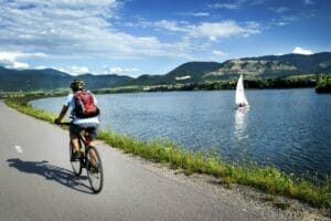 Osoba na bicykli po ceste pri jazere, neďaleko Prírodného kúpaliska Vodné dielo Žilina.