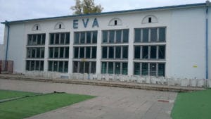 Budova s oknami a trávnatou plochou pred ňou, ktorá sa nachádza pri Termálnom kúpalisku Eva Piešťany.
