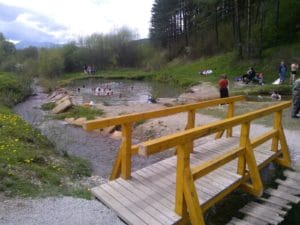 Cez pokojný rybník sa klenie drevený most.