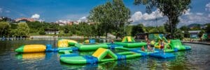 Letné plážové kúpalisko Aqualand Banská Bystrica: Partia detí hrajúcich sa na nafukovacom aquaparku v jazere.