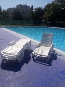 Dve biele ležadlá pri bazéne na Letnom kúpalisku Lednické Rovne.