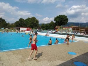 Letné kúpalisko Detva je plné partie ľudí, ktorí si užívajú osviežujúci kúpeľ vo vonkajšom bazéne.