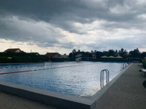 Letné kúpalisko Malacky, s bazénom pod zamračenou oblohou.