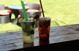 Dva drinky so slamkami na drevenom stole na Letnom kúpalisku Matadorka v Bratislave.