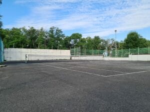 Prázdny tenisový kurt s plotom.