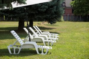 Rad bielych plastových sedačiek na trávnatej ploche Letného kúpaliska Revúca.