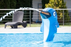 Na Letnom kúpalisku Revúca modrý delfín hravo strieka vodu do bazéna.