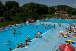 Letné kúpalisko Ryba Anička v Košiciach, kde ľudia plávajú v modrom bazéne.