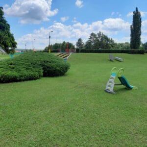 Zelená trávnatá plocha s ihriskom a kríkmi na Letnom kúpalisku Senica.