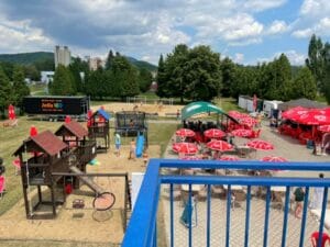 Pohľad na detské ihrisko s červenými dáždnikmi na Letnom kúpalisku Sunpark Prešov.
