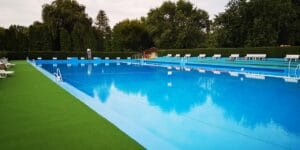 Letné kúpalisko Trebišov ponúka veľký bazén obklopený ležadlami a zelenou trávou.