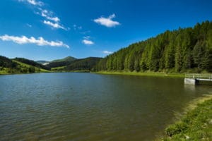 Vodná nádrž Košiare, malebné jazero uprostred vysokých stromov a majestátnych hôr.