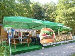 Burger stánok v lese so zelenými dáždnikmi nachádzajúci sa v blízkosti Prírodného biokúpaliska Sninské rybníky v Snine.