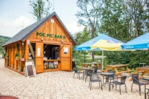 Prírodné biokúpalisko Levoča ponúka pre hostí malú drevenú budovu so stolmi a slnečníkmi.