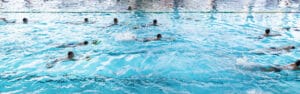 Skupina ľudí plávajúcich v krytom bazéne Krytá plaváreň Topoľčany.