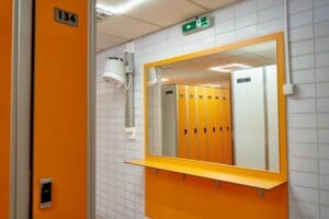 Živá oranžovo-biela kúpeľňa so zrkadlami a skrinkami, ktorá pripomína letný deň na Letnom kúpalisku Žilina.