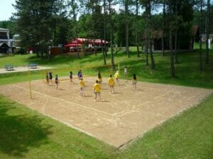 Partia ľudí hrajúcich volejbal na pieskovom ihrisku na Prírodnom biokúpalisku Sninské rybníky v Snine.