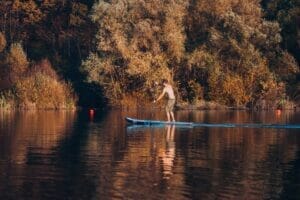 Muž, ktorý si užíva pokojné paddleboardovanie na malebnom jazere, konkrétne na Vodnej Nádrzi pri Kokošovciach.